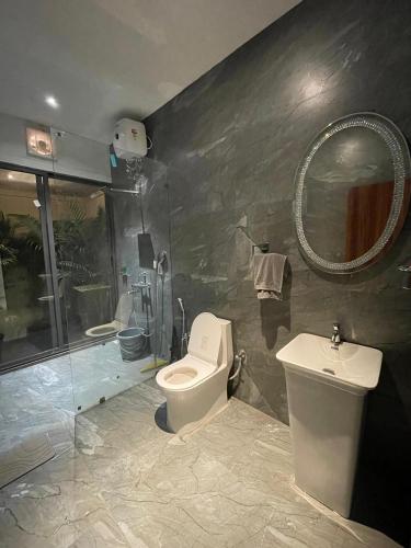 a bathroom with a toilet and a sink and a mirror at Mango Shack Villa in Trimbak