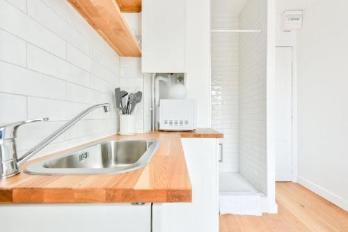 - une cuisine avec un évier et des placards blancs dans l'établissement Studio with a panoramic view of the Eiffel Tower, à Paris
