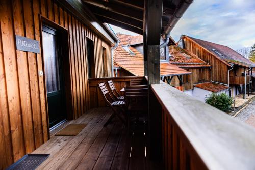 a balcony of a wooden house with two chairs at Landkulturhof Glücksbringer in Rudolstadt