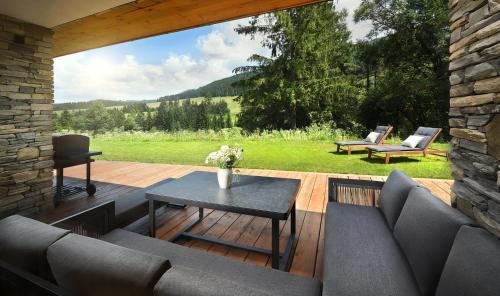 a patio with a table and chairs on a wooden deck at Chalet Oasis - Luxury Retreat at Chalets Kvačianska Dolina in Zuberec