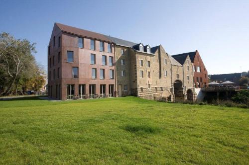 a large brick building on a field of grass at 'S Hertogenmolens Hotel in Aarschot