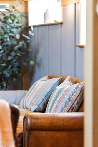 a brown couch with two pillows on it at Luxury barn Retreat - sleeps 2-4, quiet location with parking in Wymondham