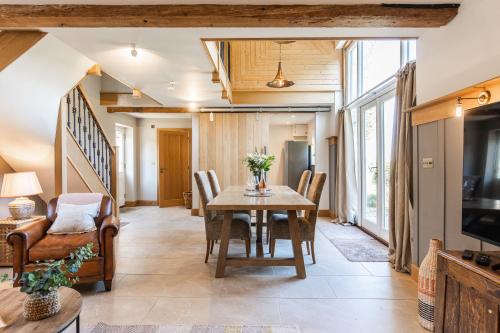 a dining room with a table and chairs and a television at Luxury barn Retreat - sleeps 2-4, quiet location with parking in Wymondham