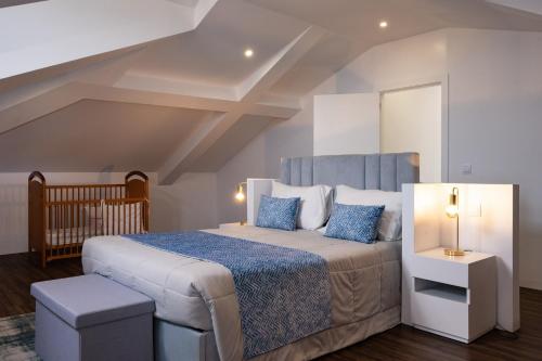 a bedroom with a large bed and a crib at Snuggly Corner by Trip2Portugal in Figueira da Foz
