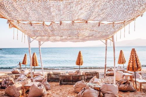 a beach with chairs and umbrellas and the ocean at Apartments enosis, Poseidon in Agia Anna Naxos