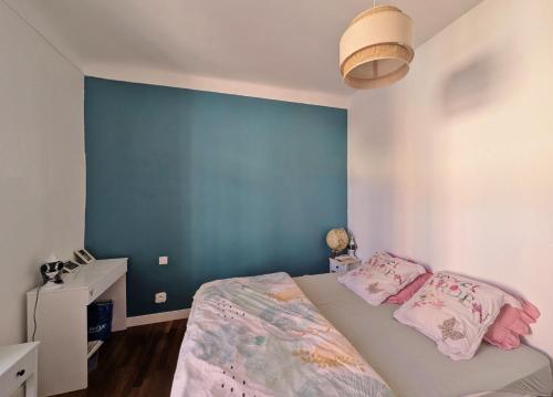 a bedroom with a blue wall and a bed with pink pillows at Le Nid Ensoleillé in Les Arcs sur Argens