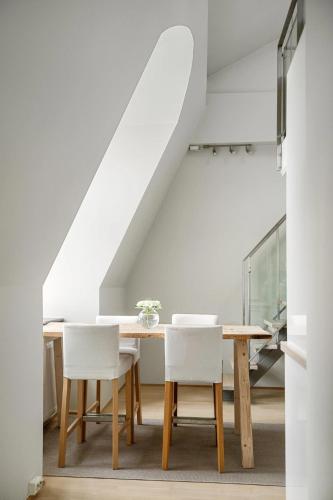a dining room with a table and white chairs at Urban Oslo Penthouse with Fireplace & City Views in Oslo