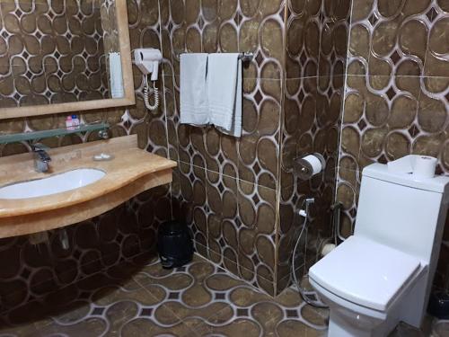 a bathroom with a sink and a toilet and a mirror at Hotel Ville Des Roses in Dilida