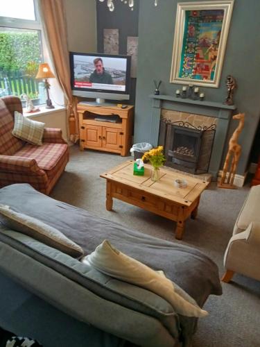a living room with a couch and a fireplace at Cottage in Saddleworth with private garden and great views in Greenfield