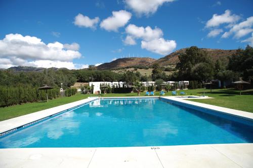 a large swimming pool with mountains in the background at TAIGA Tarifa Valdevaqueros in Tarifa