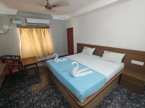 two swans sitting on a bed in a room at Hotel Picnic in Velānganni