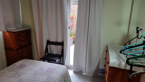 a bedroom with a bed and a chair next to a window at Habitacion Familiar en un Ático con gran terraza y,cocina ,en la playa in Burriana