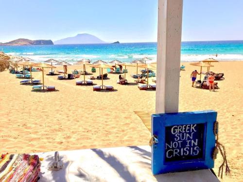 a beach with chairs and umbrellas and the ocean at C'est La Vie Beach Villa in Amoopi