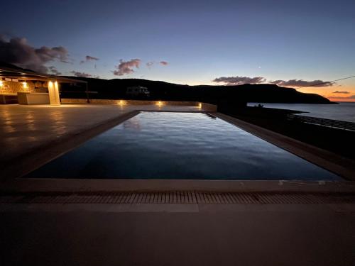 a large swimming pool with a sunset in the background at C'est La Vie Beach Villa in Amoopi