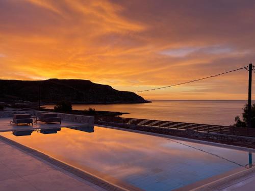 a sunset over the ocean with a swimming pool at C'est La Vie Beach Villa in Amoopi
