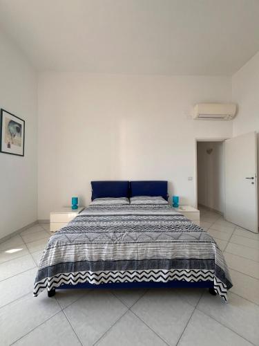 a large bed in a white room with a blue blanket at Apartment in Villa Argentina in Capri