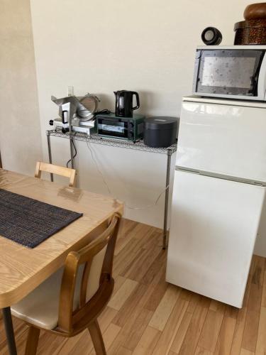 a kitchen with a white refrigerator and a table at 自然体験と石窯のある古民家民泊アジールAsyl in Hirosaki