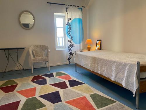 une chambre avec un lit, une chaise et un miroir dans l'établissement Le Jardinet vacances dans un coin de paradis au bord de la mer, à Peyriac-de-Mer