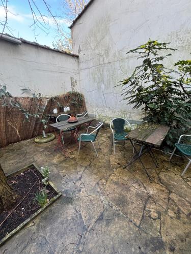 a patio with a table and chairs next to a wall at Le VILLAGE d'EZRA in Brussels