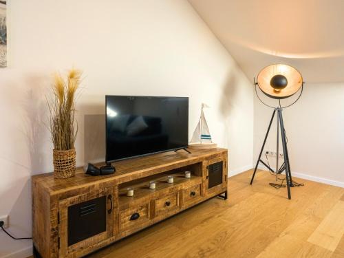 una TV a schermo piatto in cima a un centro di intrattenimento in legno di Ferienwohnung Aufhausen - die Sternengucker-Wohnung im 5-Seen-Land a Berg am Starnberger See