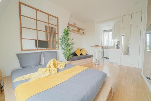 a bedroom with a bed with a yellow blanket on it at Charming studio near Paris in Saint-Ouen