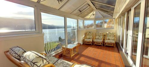 a screened in porch with chairs and a view of the water at Loch Rannoch Highland Club in Kinloch Rannoch