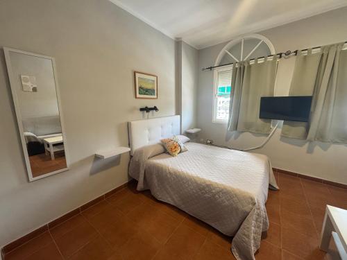 a small bedroom with a bed and a mirror at Hostal Miramar in Los Caños de Meca