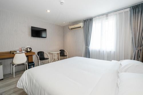 a hotel room with a white bed and a table and chairs at Aurea Delight Hotel in Phnom Penh