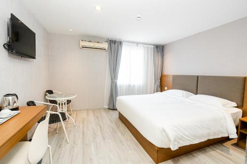 a hotel room with a bed and a desk and a television at Aurea Delight Hotel in Phnom Penh