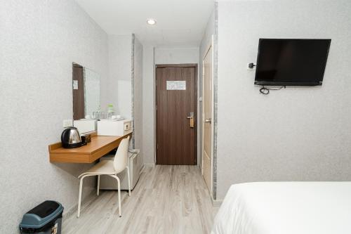 a hotel room with a desk and a television on the wall at Aurea Delight Hotel in Phnom Penh