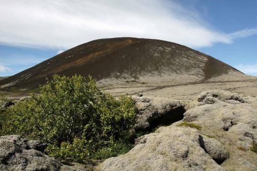 a mountain in the middle of a field with rocks at Hótel Bifröst in Bifrost