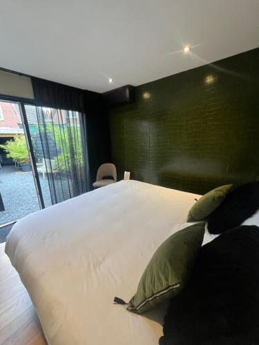 a bedroom with a large white bed with green pillows at B&B Bardot in Purmerend
