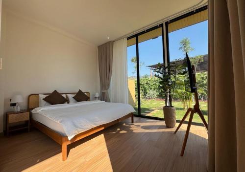 um quarto com uma cama e uma janela grande em The Nature House Botique Resort & Cafe - Ban Mung em Ban Mung