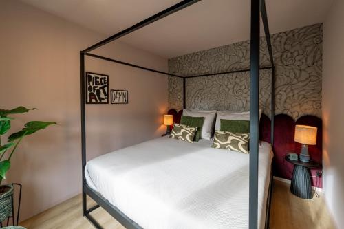a bedroom with a canopy bed with white sheets and pillows at Little Jack Boutique Studios in Valkenburg