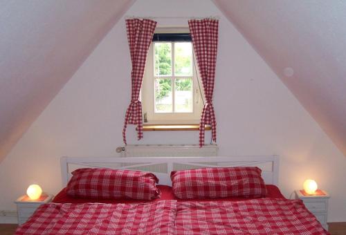 a bedroom with a bed with a window and two pillows at kleine meerZeit, süßes Knusperhäuschen mit Kaminofen in Fehmarn