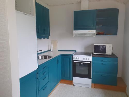 a small kitchen with blue cabinets and a microwave at Feriestedet Skovly in Klemensker