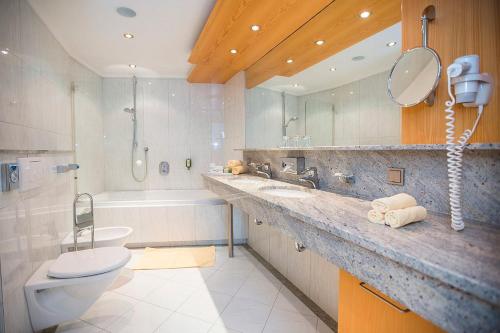 a bathroom with a sink and a toilet and a tub at EUROPÄISCHER HOF Bad Gastein in Bad Gastein