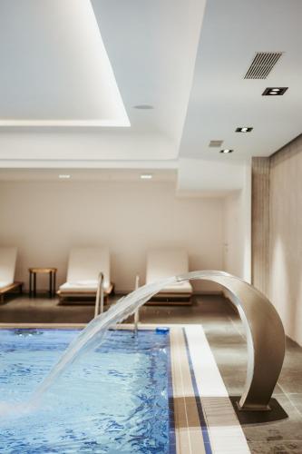 a swimming pool with a fountain in a building at Valbona Resort & Spa in Valbonë