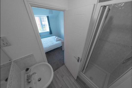 a white bathroom with a shower and a sink at Sleeps 5 - Private Garden- Free Parking in Corby