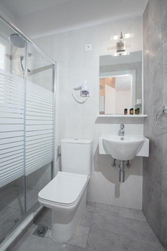 a white bathroom with a toilet and a sink at Pension Omorfi Poli in Nafplio