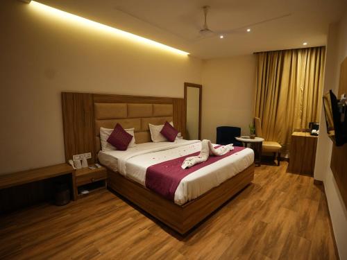 a hotel room with a large bed with pink pillows at hotel pearl wood in Zirakpur