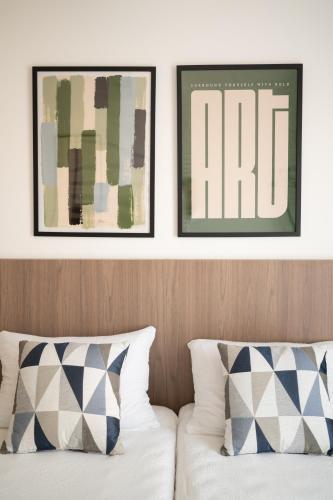 two framed art prints above a bed with pillows at Boutique Apartment - Široki Brijeg in Široki Brijeg