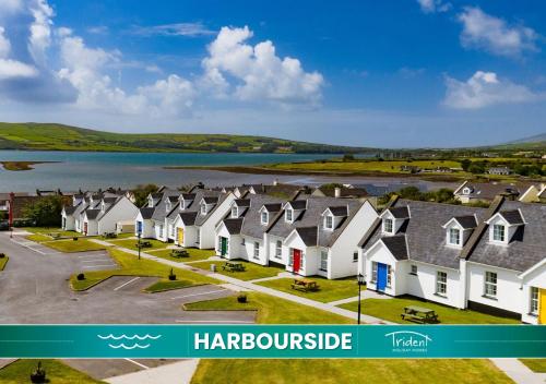 a row of houses with a lake in the background at Dingle Harbour Cottages 3 Bed - Sleeps 6 Type B by Trident Holiday Homes in Dingle