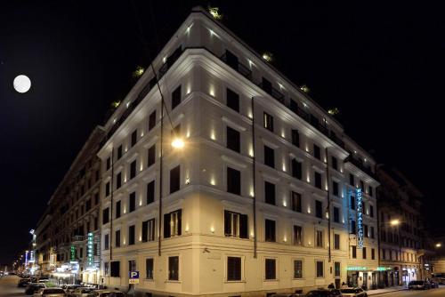 فندق بلاديوم بالاس في روما: مبنى ابيض كبير على شارع المدينة بالليل