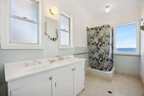 a white bathroom with a sink and two windows at Salt & Peppermint - Beachfront Escape with Stunning Views in Capel