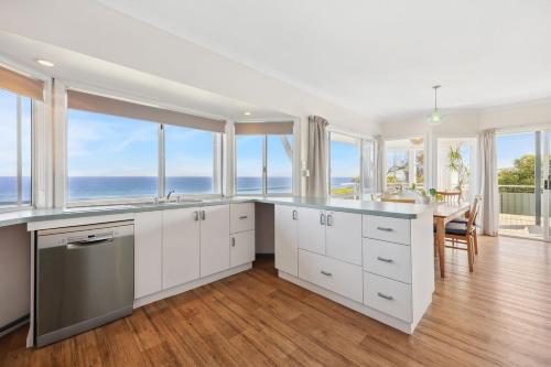 a kitchen with white cabinets and windows and the ocean at Salt & Peppermint - Beachfront Escape with Stunning Views in Capel
