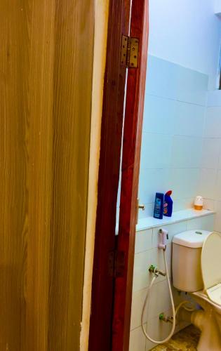 a bathroom with a toilet and a wooden door at Softlife Home Classic Studio 2 in Mombasa