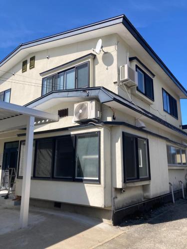 a white building with black windows and a balcony at 自然体験と石窯のある古民家民泊アジールAsyl in Hirosaki