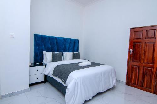 a bedroom with a large bed with a blue headboard at Morning Mist Lodge in Livingstone