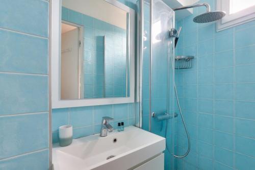 une salle de bain bleue avec un lavabo et un miroir dans l'établissement Cosy 2 BR Flat near Place d'Italie, à Paris